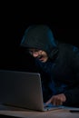 Hacker in a dark hoody sitting in front of a notebook. Computer Royalty Free Stock Photo