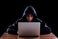 Hacker in a dark hoody sitting in front of a notebook Royalty Free Stock Photo