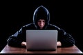 Hacker in a dark hoody sitting in front of a notebook Royalty Free Stock Photo