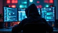 Hacker in dark room with multiple screens and coding interface. Royalty Free Stock Photo