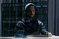 Hacker in black hood and computer trying to carry out a cyberattack over the internet Royalty Free Stock Photo