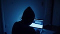 Hacker hacks programs. Computer scammer. Programmers working intently on laptop, typing in dark room with shadowy Royalty Free Stock Photo