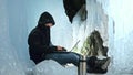 Hacker hacks the server. Man to program on laptop in ice cave. Around the mysterious ice grotto. Man hides himself in a Royalty Free Stock Photo