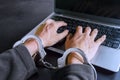 Hacker hands using laptop with tied by handcuffs