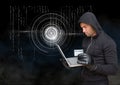 Hacker holding a credit card and using a laptop in front of digital background