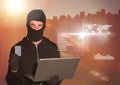 Hacker holding a credit card and using a laptop in front of digital background Royalty Free Stock Photo