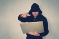 Hacker holding gun working on his computer terrorist and bandit concept. Glitch effect and copy space. Black masked hacker in the