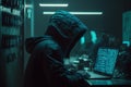 Hacker in a hood with a hidden face looks at the screen of a laptop. Hacking and malware concept.