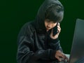 Hacker hooded call mobile phone and typing keyboard laptop computer. Royalty Free Stock Photo