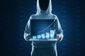 Hacker in hoodie holding laptop with growing blue financial coins chart on blurry background. Income growth, hacking, malware, Royalty Free Stock Photo