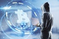 Hacker in hoodie using laptop computer with glowing bitcoin interface in blurry office interior. Hacking, theft and cryptocurrency Royalty Free Stock Photo