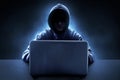Hacker in hoodie using laptop on dark backgrounds Royalty Free Stock Photo