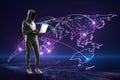 Hacker in hoodie using laptop with glowing map and connections on purple background. Global network, hacking and digital world Royalty Free Stock Photo