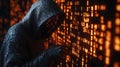 Hacker in a hoodie working against a glowing code wall at night