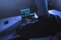 Hacker with loading bar on laptop in dark room