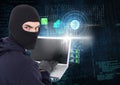 Hacker looking the lens and using a laptop in front of digital background