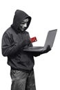 Hacker man wearing anonymous mask holding laptop and credit card Royalty Free Stock Photo