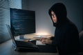 Hacker man wearing hood writing code to hack Network security system. Dangerous Hooded Hacker Breaks into Government Data Servers