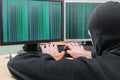 The hacker in a mask hacks the computer system. Zeros and ones are shown on the screen