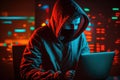 Hacker in a mask and hood looks at the laptop screen. Hacking and malware concept.