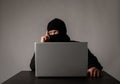 Hacker in mask using a laptop