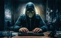 Hacker masked sitting at keyboard with cloaking hoodie in dark environment Royalty Free Stock Photo