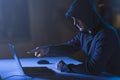 Hacker pointing at laptop computer in dark room