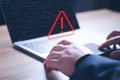 Hacker or programmer using laptop with triangle caution warning sign, coding, cryptography, hacker, crime, virus, for notification Royalty Free Stock Photo