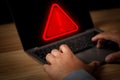 Hacker or programmer using laptop with triangle caution warning sign, coding, cryptography Royalty Free Stock Photo