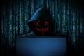 Hacker with red glowing mask behind notebook laptop in front of blue source binary code background internet cyber hack attack Royalty Free Stock Photo