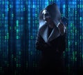 a hacker in a scary mask and hood stands against the background of a digital binary code