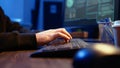 Hacker in secret underground shelter typing on keyboard, close up
