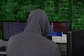 A hacker sits behind computer monitors on an abstract background, attacking and hacking servers with a virus. Creation and dissemi