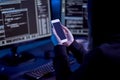 hacker with smartphone and computers in dark room Royalty Free Stock Photo