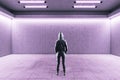 Hacker standing in futuristic hall with empty wall and neon paints Royalty Free Stock Photo