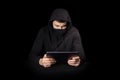 Hacker with tablet PC initiating cyber attack, on black