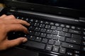 Hacker typing code on laptop keyboard with his fingers Royalty Free Stock Photo