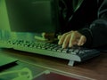 Hacker Typing on Keyboard with Dark Green Light Background Royalty Free Stock Photo