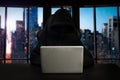 Hacker using computer with digital interface while sitting at desk of blurry interior. Hacking and thief concept Royalty Free Stock Photo