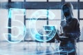 Hacker using laptop with abstract glowing 5G hologram on blurry office interior background. Mobile internet speed, hacking, data Royalty Free Stock Photo