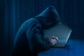 Hacker. Hacker using laptop on dark binary code digital background. Faceless hooded anonymous computer hacker. Hacking and malware Royalty Free Stock Photo