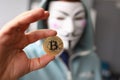 Hacker wear anonymus mask hold bitcoin in hand