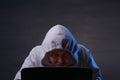Hacker wearing grey hoodie using laptop computer