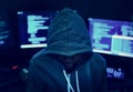 Hacker wearing a hoody with computers in the background