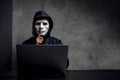 Hacker wearing a white mask in front of his computer. hacker hacks network, Space for text Royalty Free Stock Photo