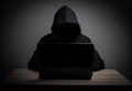 Hacker work front of his laptop computer with dark face. Royalty Free Stock Photo