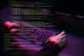 Hacker working with computer in dark room with digital interface around. Image with glitch effect. Royalty Free Stock Photo