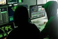 Hackers working on computers showing world maps and security camera footage Royalty Free Stock Photo