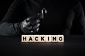 Hacking and hacker. The word hacking on wooden blocks with a hacker holding an open padlock Royalty Free Stock Photo