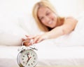 She had a good nights sleep. A beautiful young woman turning off her alarm clock in the morning. Royalty Free Stock Photo